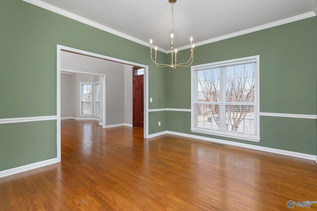 unfurnished room with wood-type flooring, ornamental molding, and a notable chandelier