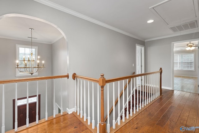 corridor with ornamental molding, hardwood / wood-style floors, and a notable chandelier