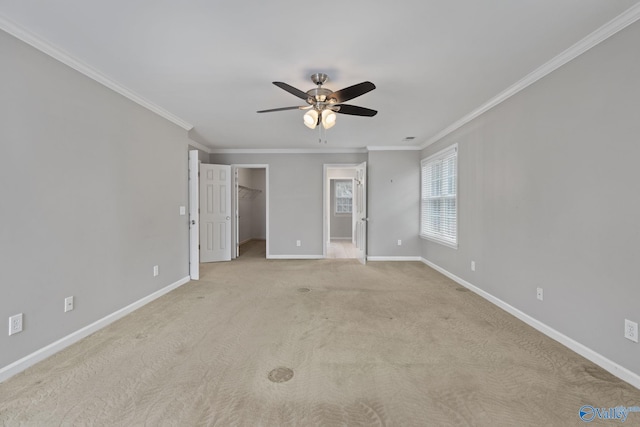 unfurnished bedroom with crown molding, a walk in closet, light colored carpet, and ceiling fan