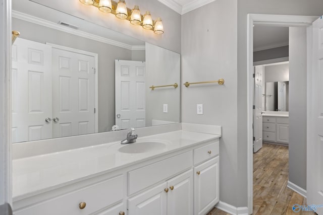 bathroom featuring hardwood / wood-style flooring, crown molding, and vanity