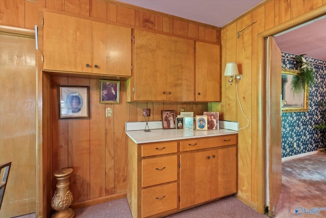 kitchen featuring wood walls, brown cabinets, light countertops, and baseboards