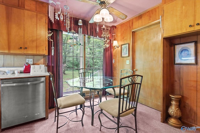 dining space featuring a ceiling fan, wooden walls, and light colored carpet