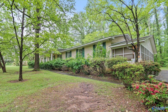 view of front of house with a sunroom, a front yard, and brick siding
