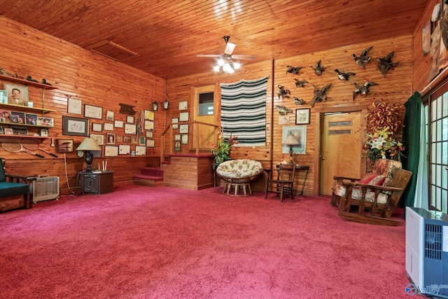 living area with wood walls, carpet, a ceiling fan, and wood ceiling