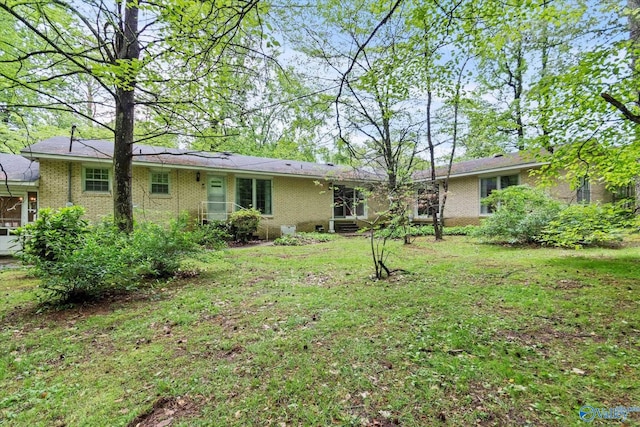 rear view of house featuring brick siding and a lawn
