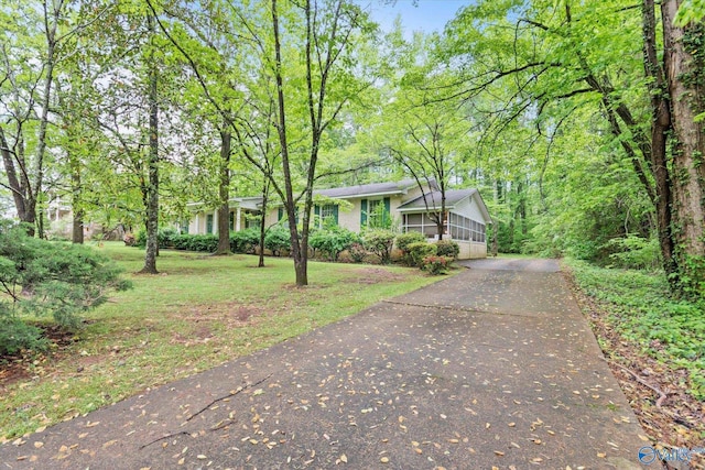 view of front of property featuring driveway, a front yard, and a sunroom