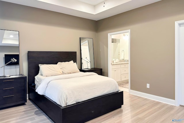 bedroom with ensuite bath and light wood-type flooring