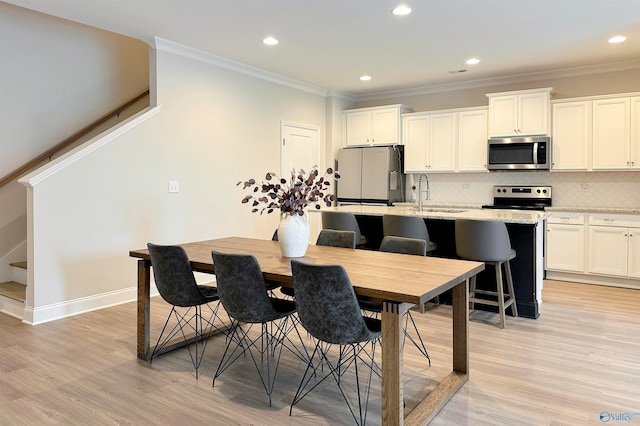 dining space featuring sink, ornamental molding, and light hardwood / wood-style flooring