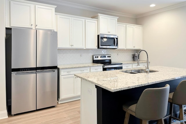 kitchen with stainless steel appliances, white cabinetry, sink, and an island with sink