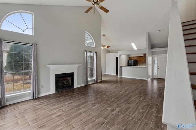 unfurnished living room featuring ceiling fan and a high ceiling