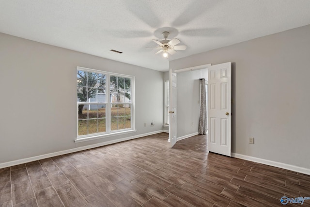 unfurnished room with ceiling fan, dark hardwood / wood-style flooring, and a textured ceiling