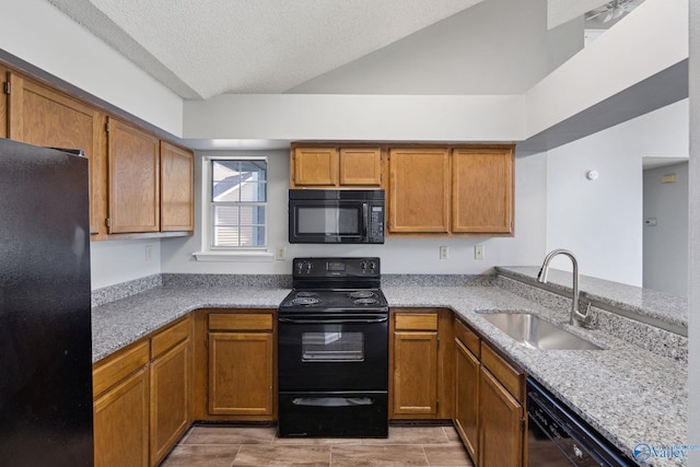 kitchen featuring kitchen peninsula, light stone counters, a textured ceiling, sink, and black appliances