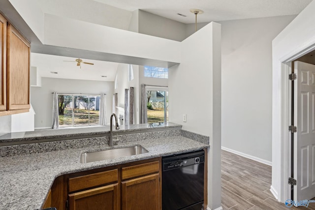 kitchen featuring light stone counters, ceiling fan, sink, dishwasher, and hanging light fixtures