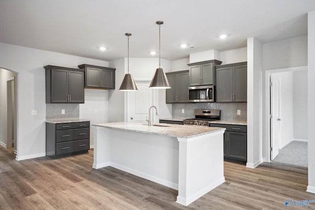 189 Saddle St, New Market, AL 35761 - kitchen with stainless steel appliances, tasteful backsplash, light wood finished floors, a center island with sink, and arched walkways