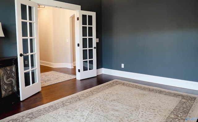 spare room with dark hardwood / wood-style floors and french doors