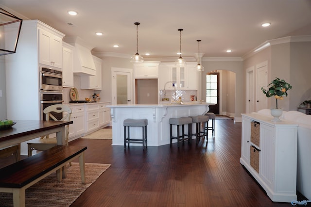 kitchen with pendant lighting, white cabinetry, backsplash, a center island, and custom range hood