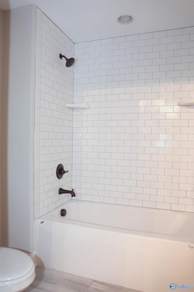 bathroom featuring toilet and tiled shower / bath