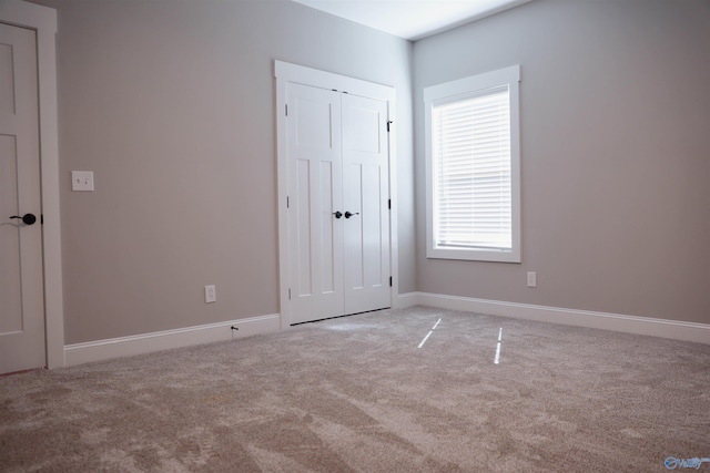 unfurnished bedroom with light carpet and a closet