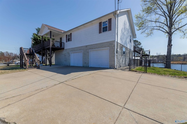 view of property exterior featuring a garage, fence, driveway, and stairs