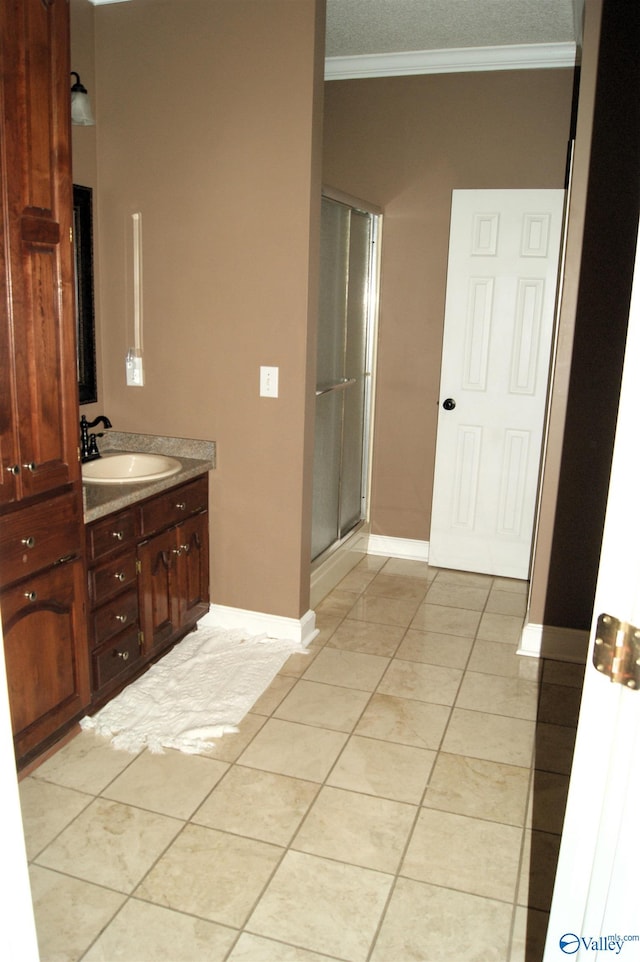 bathroom with tile patterned floors, a stall shower, crown molding, baseboards, and vanity