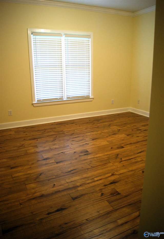 spare room featuring dark wood finished floors, baseboards, and ornamental molding