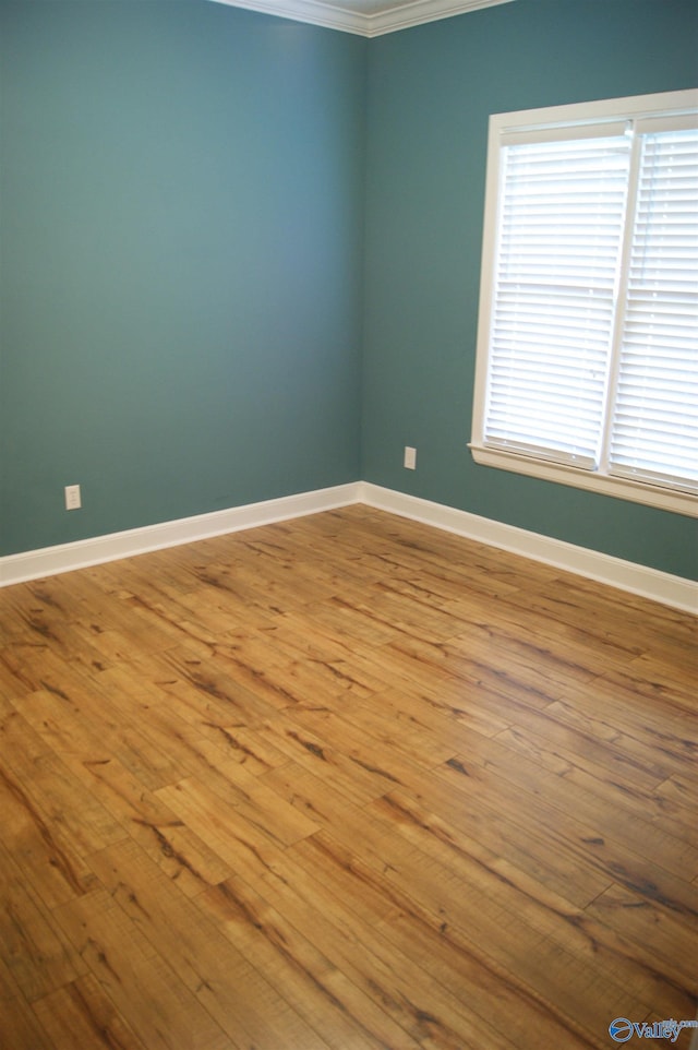 unfurnished room featuring crown molding, hardwood / wood-style flooring, plenty of natural light, and baseboards