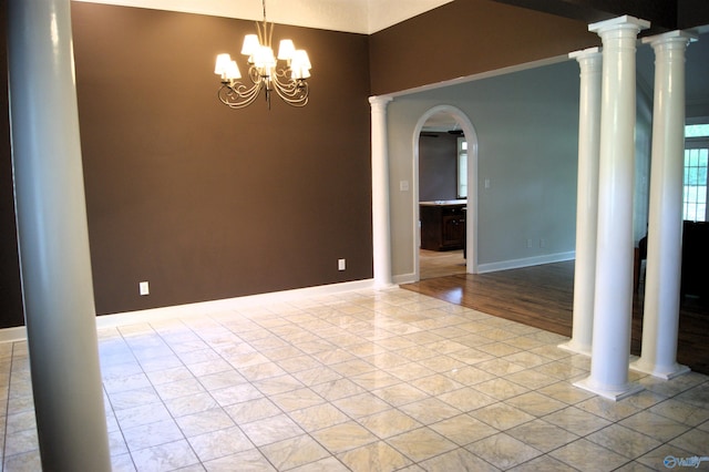 spare room with baseboards, arched walkways, and a chandelier