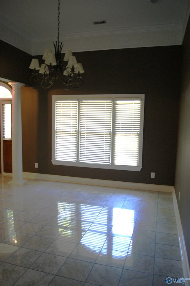 empty room featuring a chandelier, crown molding, baseboards, and decorative columns