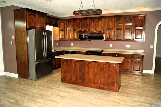 kitchen featuring black stove, stainless steel microwave, light countertops, and freestanding refrigerator