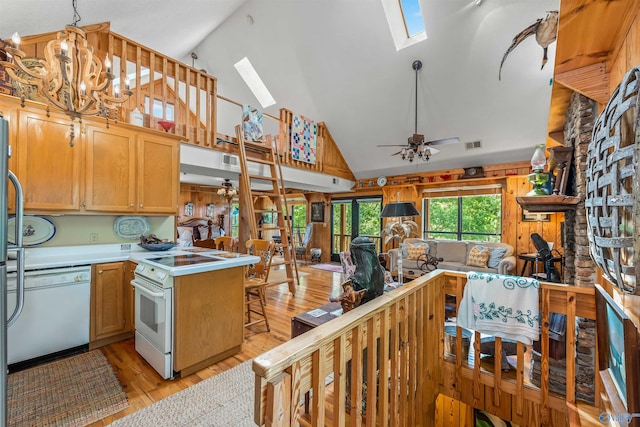 kitchen with a skylight, white appliances, light wood-type flooring, ceiling fan with notable chandelier, and high vaulted ceiling