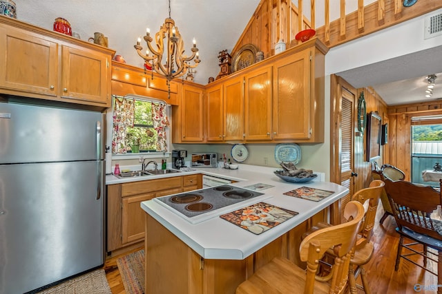 kitchen with stainless steel fridge, a kitchen breakfast bar, sink, and decorative light fixtures