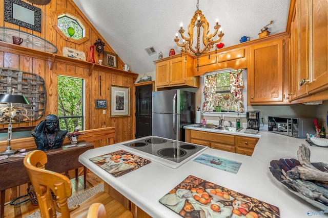 kitchen with sink, vaulted ceiling, stainless steel fridge, a kitchen breakfast bar, and pendant lighting