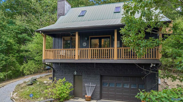 rear view of property featuring a balcony and a garage