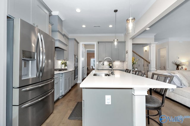 kitchen featuring hardwood / wood-style floors, sink, a kitchen bar, appliances with stainless steel finishes, and backsplash