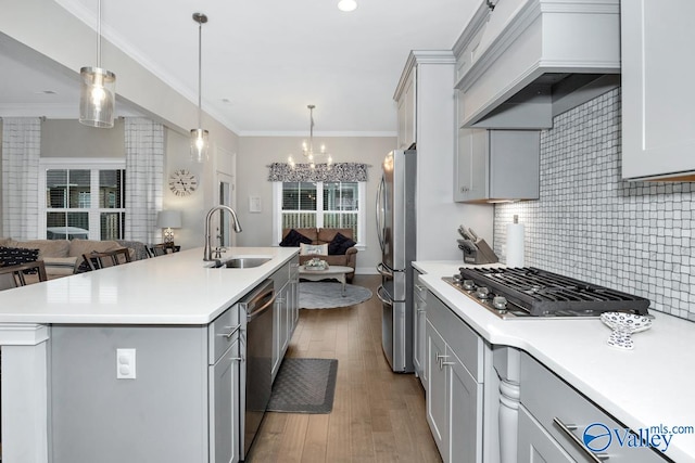 kitchen featuring premium range hood, tasteful backsplash, an island with sink, sink, and light hardwood / wood-style floors