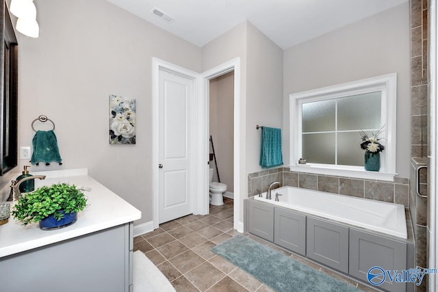 bathroom with a tub, vanity, tile patterned flooring, and toilet