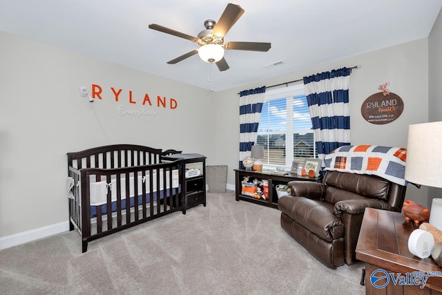 bedroom featuring light colored carpet, a crib, and ceiling fan