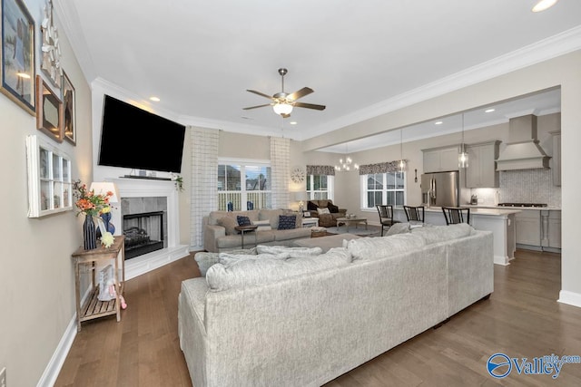 living room with crown molding, ceiling fan with notable chandelier, and wood-type flooring