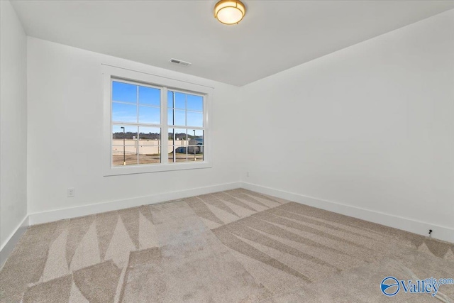 carpeted spare room with visible vents and baseboards