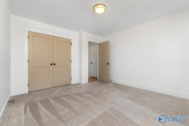 unfurnished bedroom with a closet, light colored carpet, and baseboards