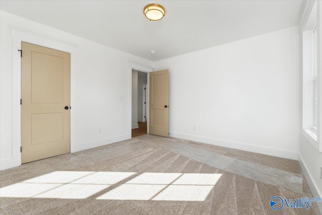 spare room with light colored carpet and baseboards