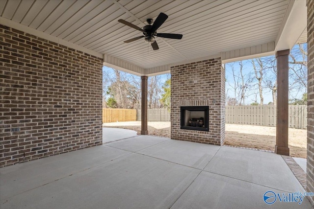 view of patio with an outdoor brick fireplace, ceiling fan, and a fenced backyard