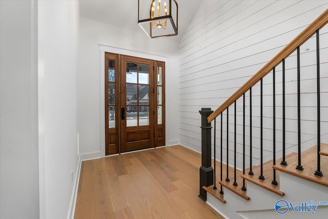 entrance foyer featuring a chandelier, stairway, baseboards, and wood finished floors