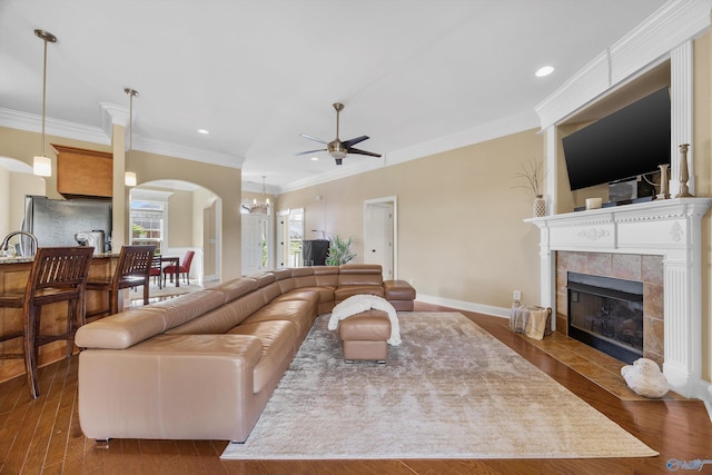 225 Nettles Dr NW, Madison, AL 35757 - living room featuring arched walkways, a tiled fireplace, a ceiling fan, recessed lighting, and crown molding