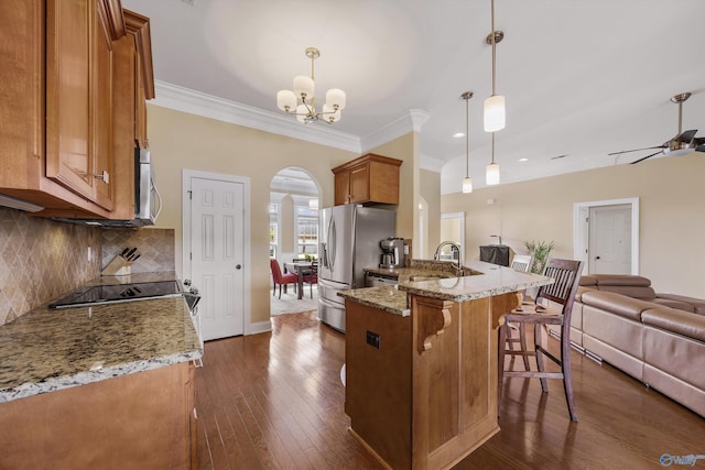 225 Nettles Dr NW, Madison, AL 35757 - kitchen with brown cabinetry, appliances with stainless steel finishes, arched walkways, open floor plan, and a peninsula