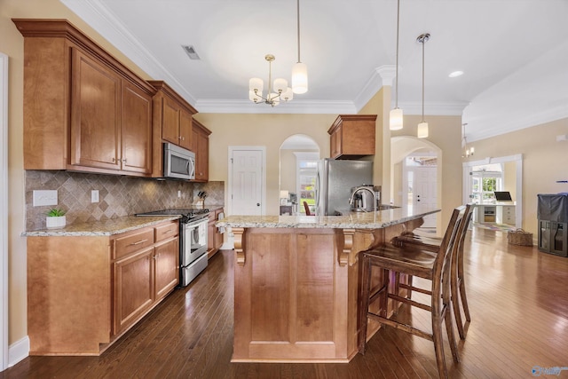 225 Nettles Dr NW, Madison, AL 35757 - kitchen with stainless steel appliances, arched walkways, dark wood-type flooring, brown cabinetry, and ornamental molding