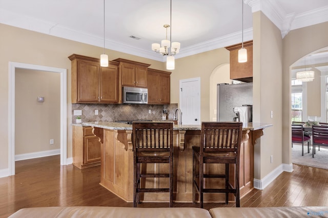 225 Nettles Dr NW, Madison, AL 35757 - kitchen featuring stainless steel appliances, arched walkways, brown cabinetry, dark wood-type flooring, and a chandelier
