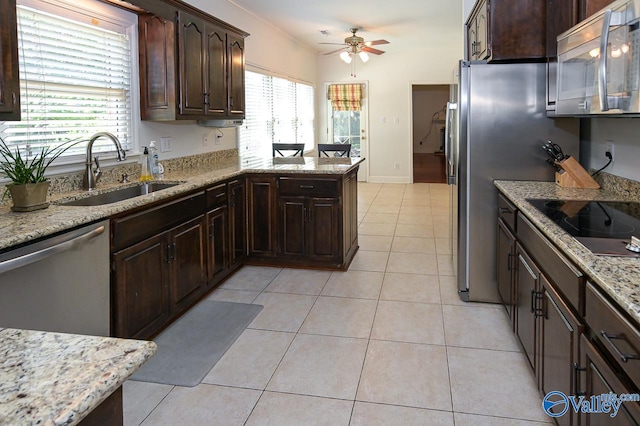 kitchen featuring sink, light tile patterned floors, appliances with stainless steel finishes, light stone counters, and ceiling fan