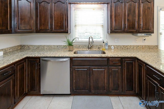 kitchen with stainless steel dishwasher, sink, dark brown cabinets, and light stone counters