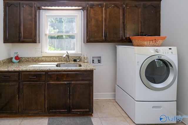 laundry area with sink, light tile patterned floors, washer / dryer, and cabinets